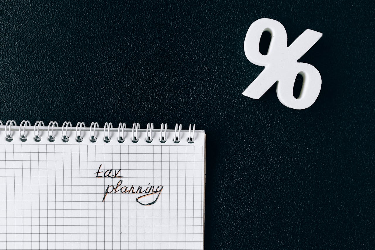 A notebook with tax planning written on a grid paper next to a percent symbol on a black background.